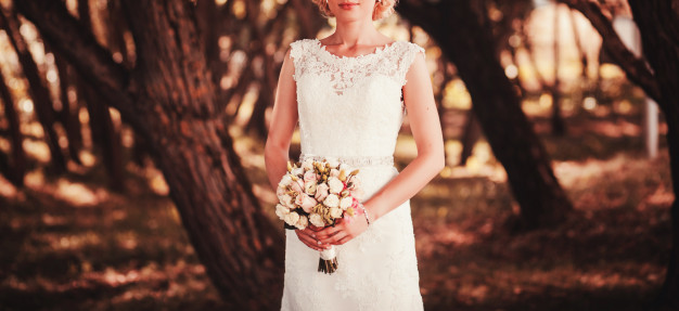 bride-white-dress-holding-bouquet-flowers_84738-2490